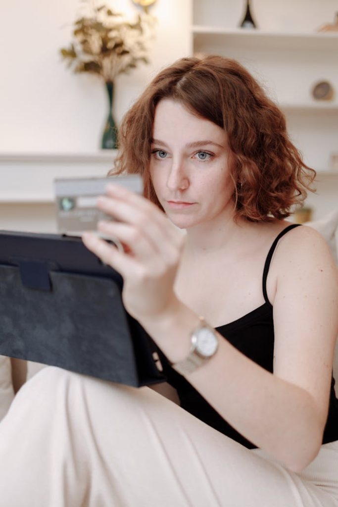 pexels photo 6238096 A woman using a tablet for online shopping, holding a credit card in a cozy indoor setting.